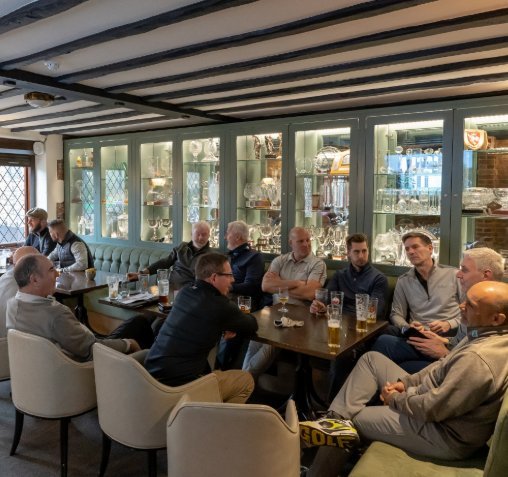 Clubhouse interior with trophy cases and golfers at the bar