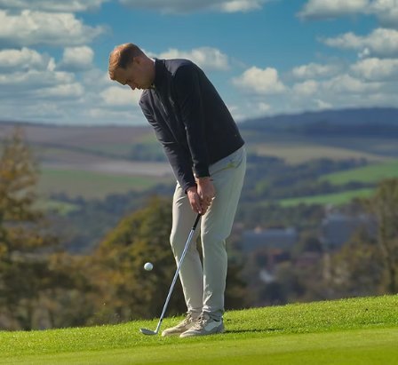 Golfer putting with the South Downs in the background